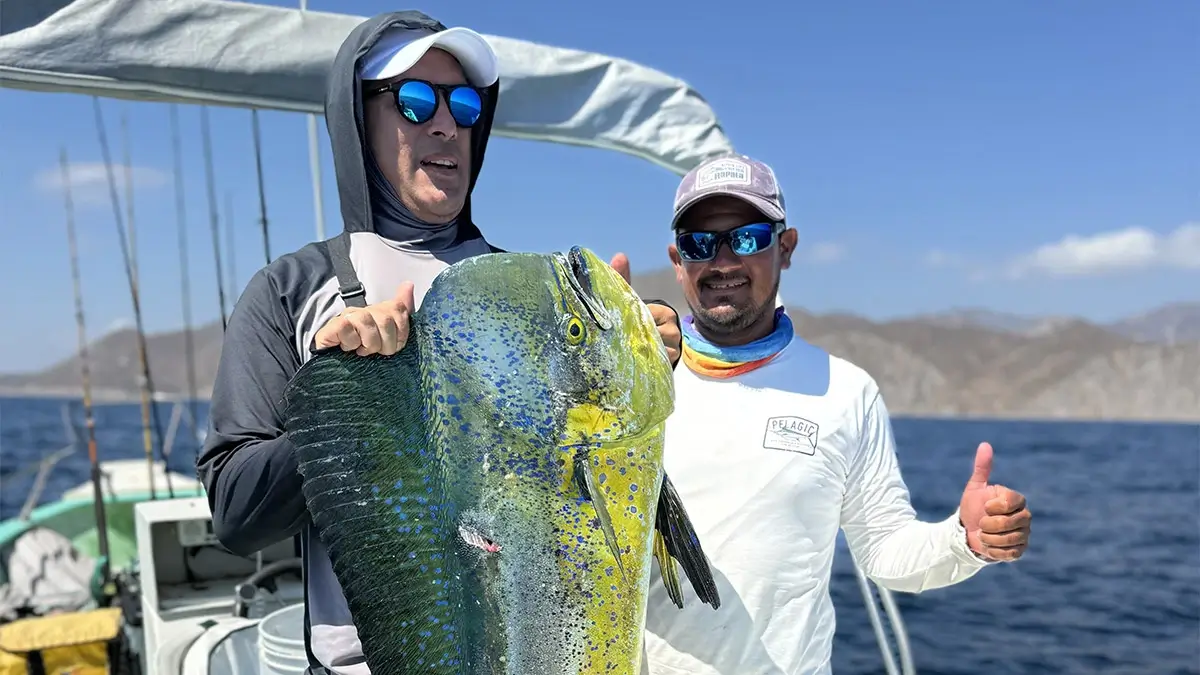 Capitán y cliente sosteniendo un dorado.